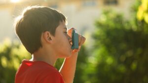 Asthmatic child with inhaler outside to avoid asthma-related symptoms